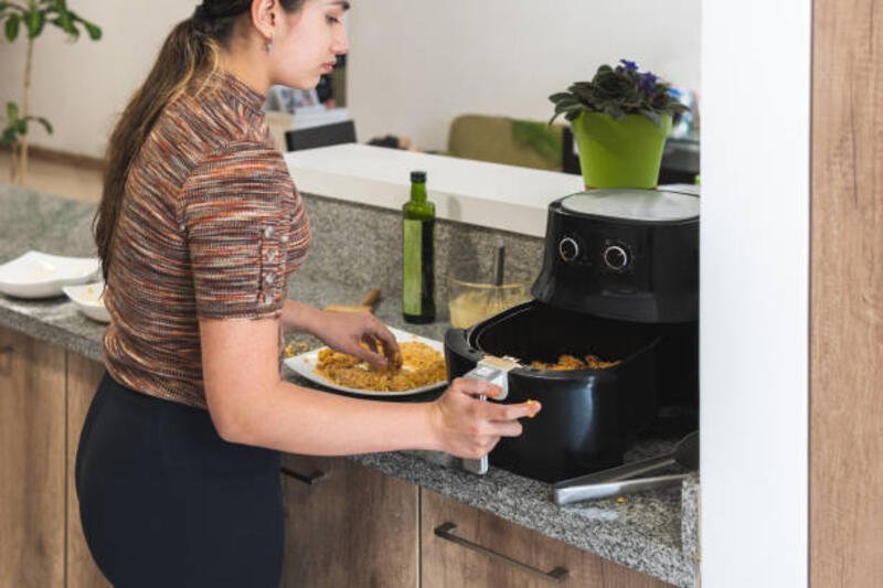 wanita remaja menyiapkan ayam goreng dalam panci penggorengan dalam di dapur rumahnya - penggoreng udara potret stok, foto, &amp; gambar bebas royalti