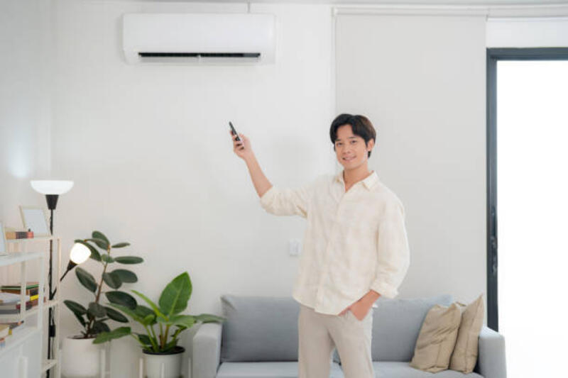 young man using remote to adjust air conditioning at home - ac potret stok, foto, &amp; gambar bebas royalti