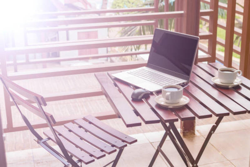 Selamat pagi! Laptop dan kopi di atas meja. Cuaca cerah