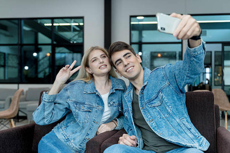 pasangan-muda-yang-tersenyum-berswafoto-bersama-di-lounge-modern-mengenakan-jaket-denim-yang.jpg (612×408)