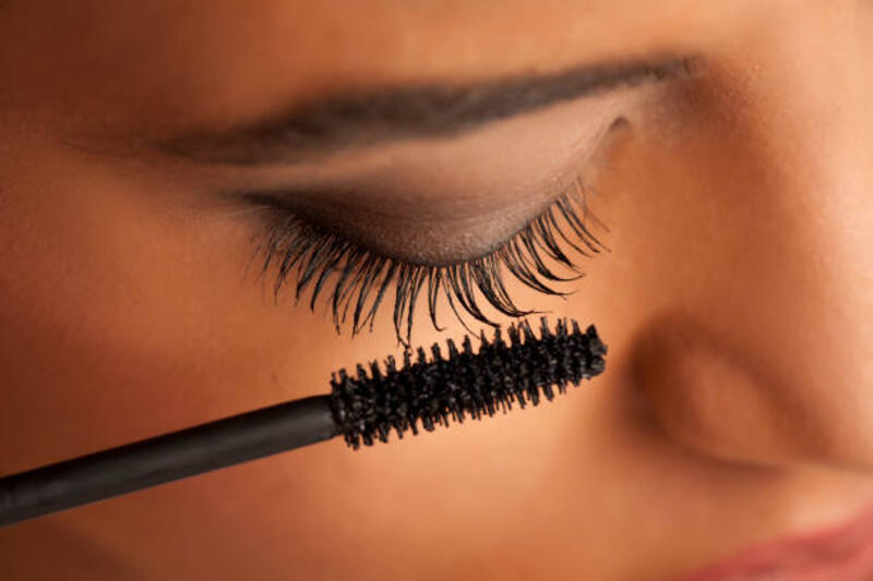 closeup of a young dark-skinned woman applying mascara on a white background closeup of a young dark-skinned woman applying mascara on a white background mascara stock pictures, royalty-free photos &amp; images