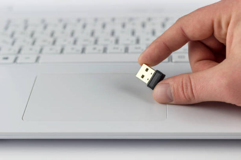 flash drive mini di tangan pada latar belakang keyboard laptop