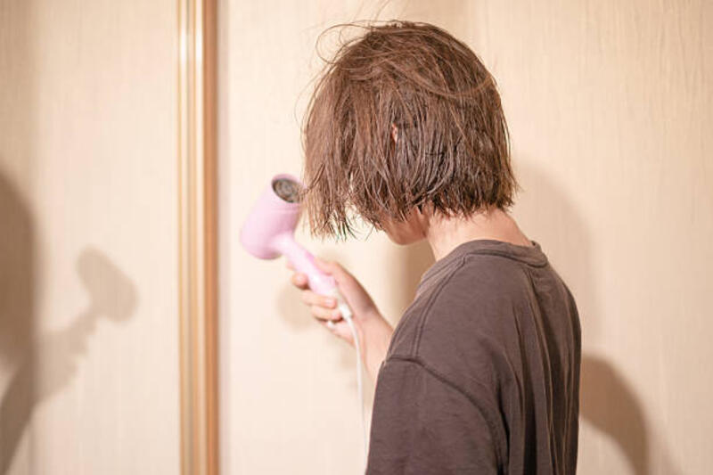 remaja laki-laki mengeringkan rambutnya dengan pengering rambut di kamar mandi yang cukup terang setelah mandi selama sore hari yang santai - hair dryer rambut basah potret stok, foto, &amp; gambar bebas royalti