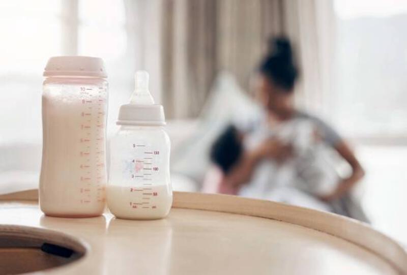bidikan defokus seorang ibu muda yang memberi makan putrinya di sofa - baby bottle potret stok, foto, &amp; gambar bebas royalti