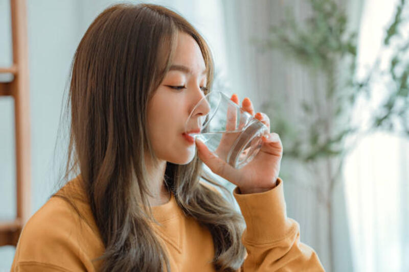 wanita asia minum air memulai hari baru dengan kebiasaan hidup sehat, wanita memegang gelas minum air mineral bersih alami di ruang tamu di rumah pagi, konsep perawatan kesehatan gaya hidup - minum air putih potret stok, foto, &amp; gambar bebas royalti