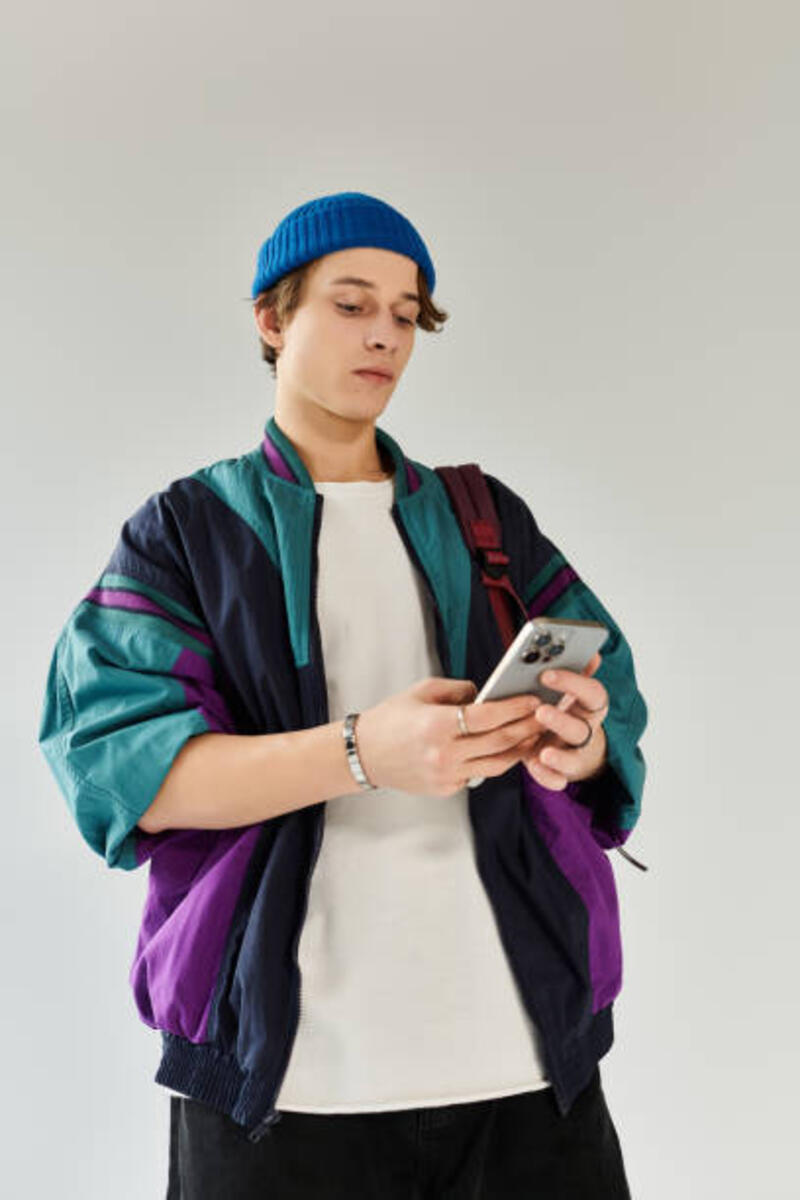 pemuda bergaya dengan pakaian semarak terlibat dengan ponselnya di studio - bomber jacket potret stok, foto, &amp; gambar bebas royalti