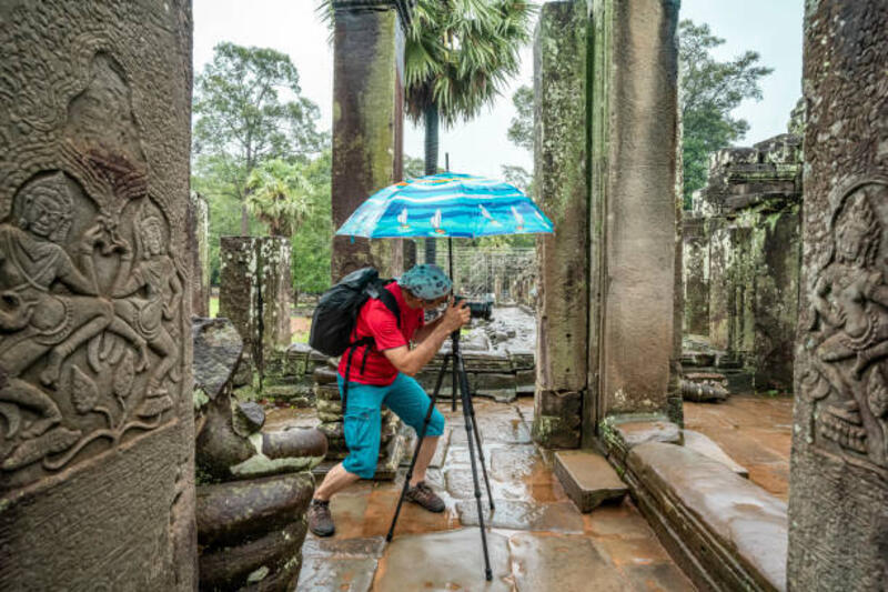 fotografer, berfoto di bawah hujan dengan payung di kuil bayon di angkor wat - camera tripod rain potret stok, foto, &amp; gambar bebas royalti