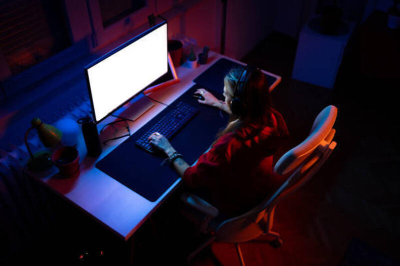Di atas tampilan wanita riang bermain video game di PC rumah.