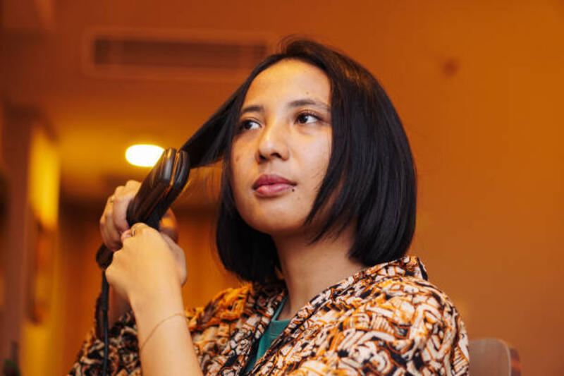 wanita dengan rambut hitam pendek menggunakan pelurus rambut untuk styling, merawat rambutnya - hair straightener potret stok, foto, &amp; gambar bebas royalti