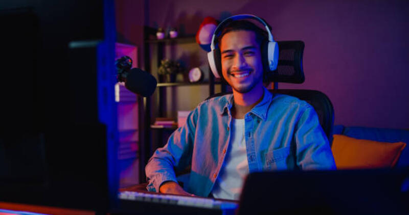 happy asia guy gamer memakai headphone partisipasi bermain video game warna-warni neon lampu komputer dan tersenyum melihat kamera di ruang tamu di malam hari modern rumah. - gaming headphone potret stok, foto, & gambar bebas royalti