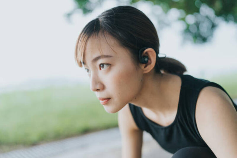 seorang wanita dewasa muda asia timur fokus pada posisi start berjongkok sebelum berlari - wear tws earhook running potret stok, foto, &amp; gambar bebas royalti
