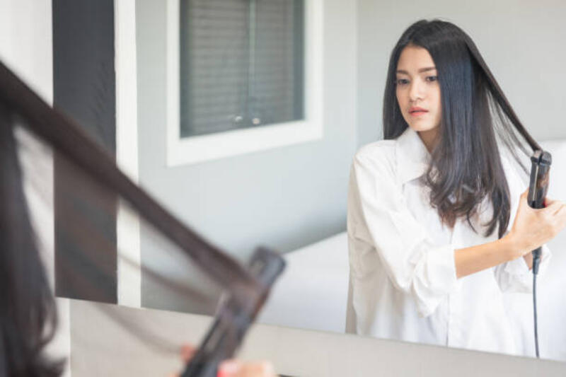 wanita cantik muda berpakaian dan menggunakan pelurus rambut di depan cermin di kamar - catokan rambut potret stok, foto, &amp; gambar bebas royalti