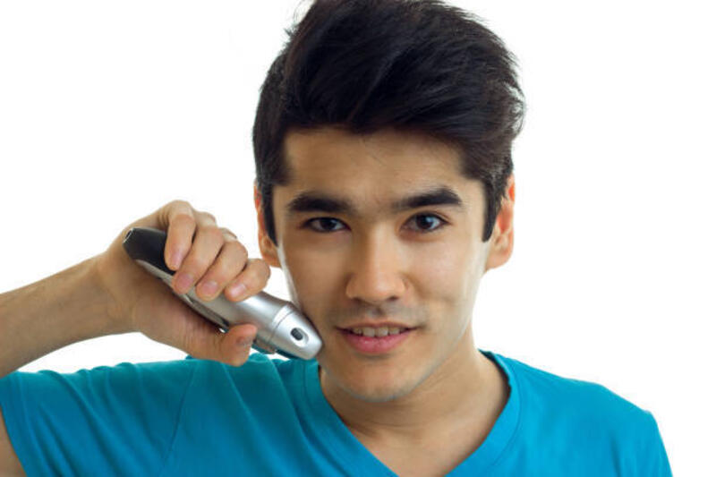 Potret seorang pemuda tampan yang melihat ke arah kamera sambil tersenyum dan mencukur gagah jenggot