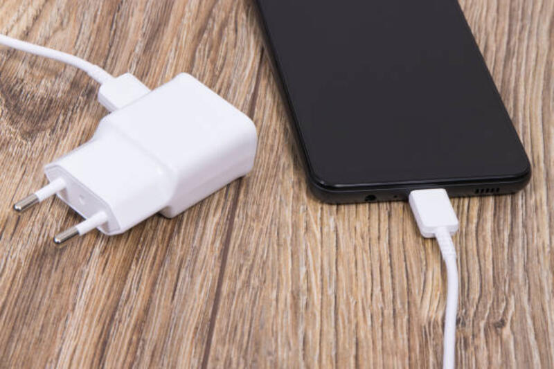 Smartphone dan charger digunakan untuk mengisi baterai kosong. Konsep pengisian daya berbagai perangkat