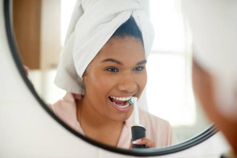 Shot of a young woman brushing her teeth with an electric toothbrush at home Everyone loves to have a natural looking white smile electric toothbrush stock pictures, royalty-free photos &amp; images