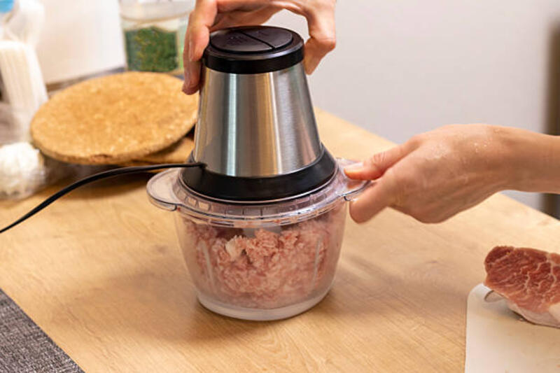 wanita mencincang daging di perajang listrik di atas meja dapur. - mini chopper for meat potret stok, foto, & gambar bebas royalti