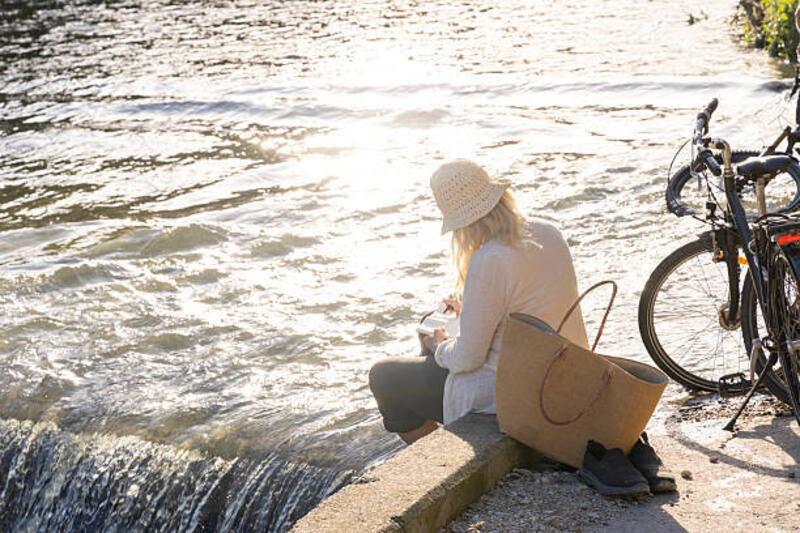 wanita dewasa menggambar di buku catatan di tepi sungai, liguria - wanita tua tas bahu potret stok, foto, &amp; gambar bebas royalti