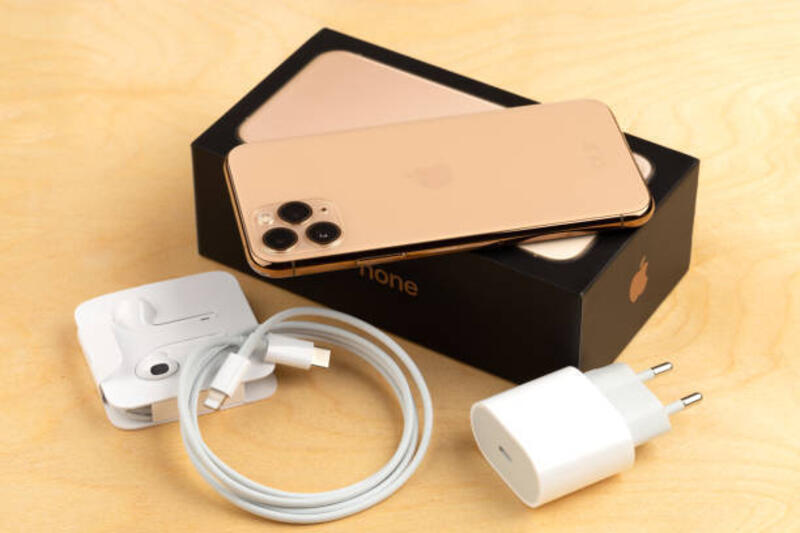 apple iphone 11 pro di permukaan kayu.  smartphone baru dari perusahaan apple close-up. smartphone dan kotak dengan kit dari itu. - iphone power charge potret stok, foto, &amp; gambar bebas royalti