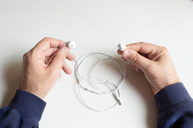 tangan pria memegang headphone in-ear dengan latar belakang abu-abu. - mencabut earphone kabel potret stok, foto, &amp; gambar bebas royalti