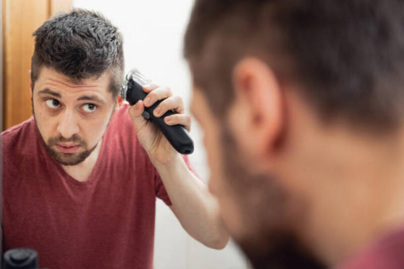 Seorang pria memotong rambutnya di kepalanya dengan pisau cukur listrik karena isolasi diri