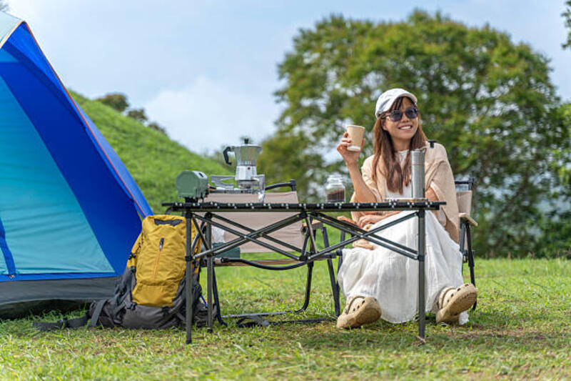 happy asian woman enjoying coffee while camping in nature - use hat for outdoor activity potret stok, foto, & gambar bebas royalti