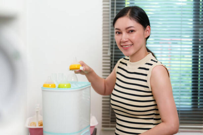 ibu menyusui botol susu bayi ke dalam steam sterilizer - alat sterilisasi botol bayi potret stok, foto, &amp; gambar bebas royalti