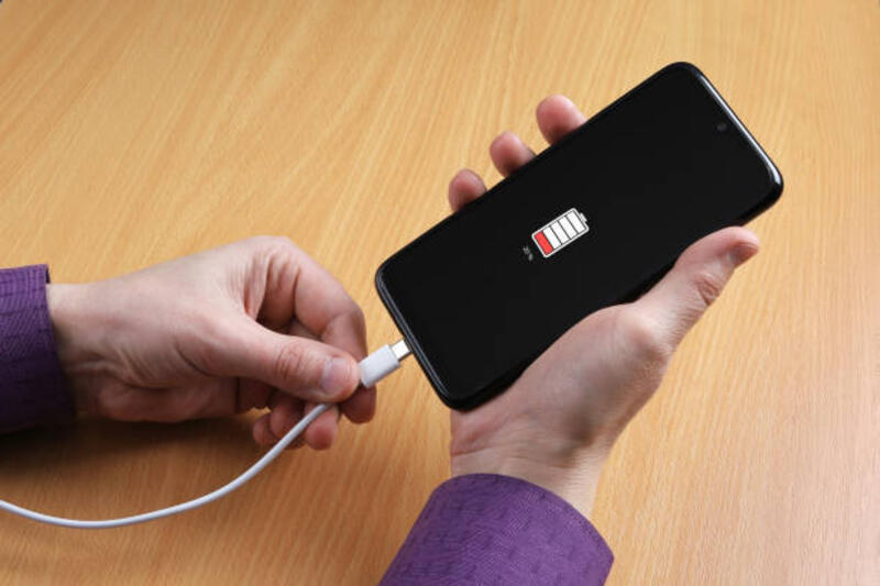 Manusia menghubungkan kabel pengisian daya ke smartphone foto stok