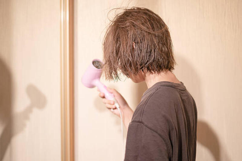 remaja laki-laki mengeringkan rambutnya dengan pengering rambut di kamar mandi yang cukup terang setelah mandi selama sore hari yang santai - rambut basah pakai hair dryer potret stok, foto, &amp; gambar bebas royalti