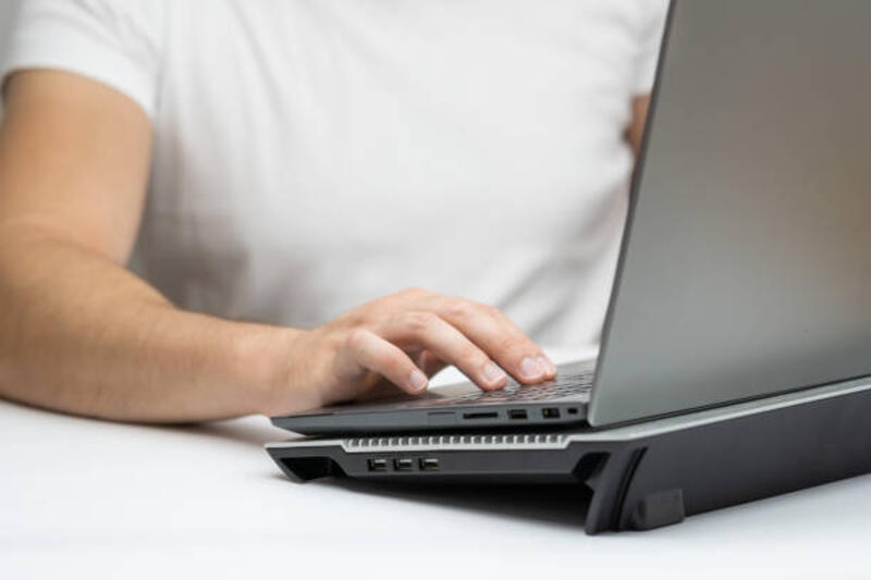 Close up tangan pria menggunakan laptop berdiri di atas dudukan pendingin foto stok