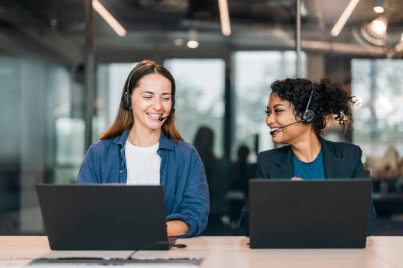cheerful-young-female-customer-service-representative-working-by-colleague-at-desk-in-call.jpg (612×408)