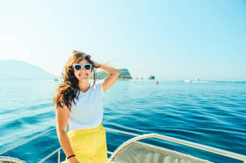 wanita cantik muda di laut hidung perahu dengan pegunungan dan pulau di latar belakang