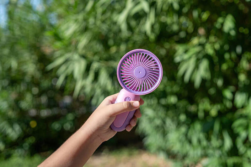 hand holding portable mini fan outdoors in sunlight - kipas angin mini portable potret stok, foto, & gambar bebas royalti