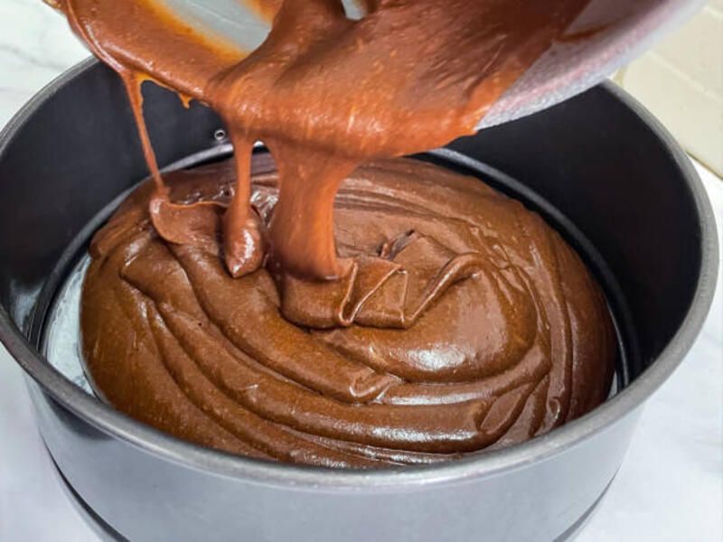 gambar close-up adonan kue bolu victoria cokelat buatan sendiri, campuran mentega, gula, tepung, dan kakao yang dituangkan dari mangkuk pencampur plastik ke dalam kaleng kue anti lengket yang dilapisi dengan kertas perkamen tahan minyak, meja dapur efek ma - adonan kue bolu potret stok, foto, &amp; gambar bebas royalti