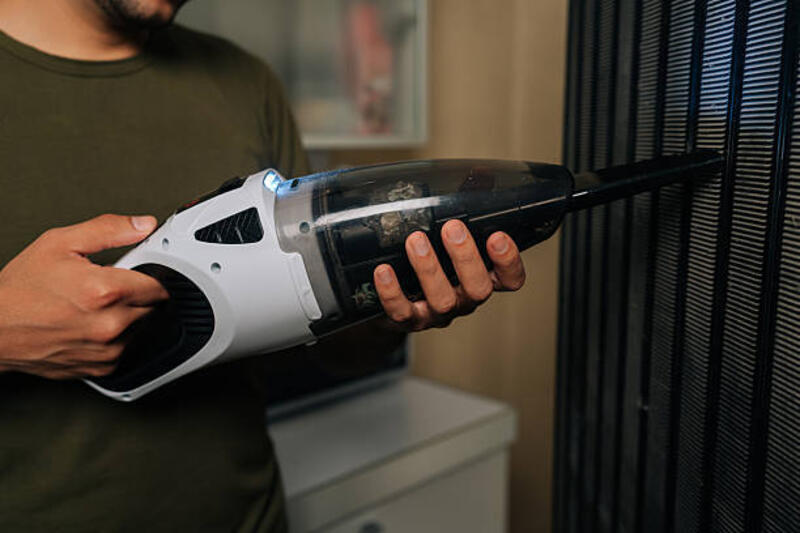 foto pembantu rumah tangga yang dipotong menggunakan penyedot debu portabel untuk menghilangkan debu dan kotoran dari panggangan lemari es, memastikan kebersihan dan kebersihan di dapur rumah. - portable vacuum cleaner potret stok, foto, & gambar bebas royalti