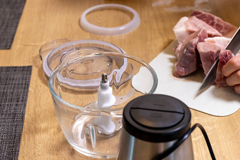 woman cuts the meat, prepares it to grind it in electrical chopper. - mini chopper for meat potret stok, foto, & gambar bebas royalti