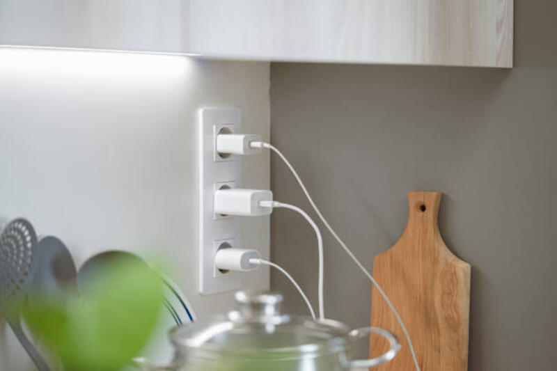 beberapa pengisi daya baterai dicolokkan ke stopkontak dinding dapur - smartphone adaptor potret stok, foto, &amp; gambar bebas royalti