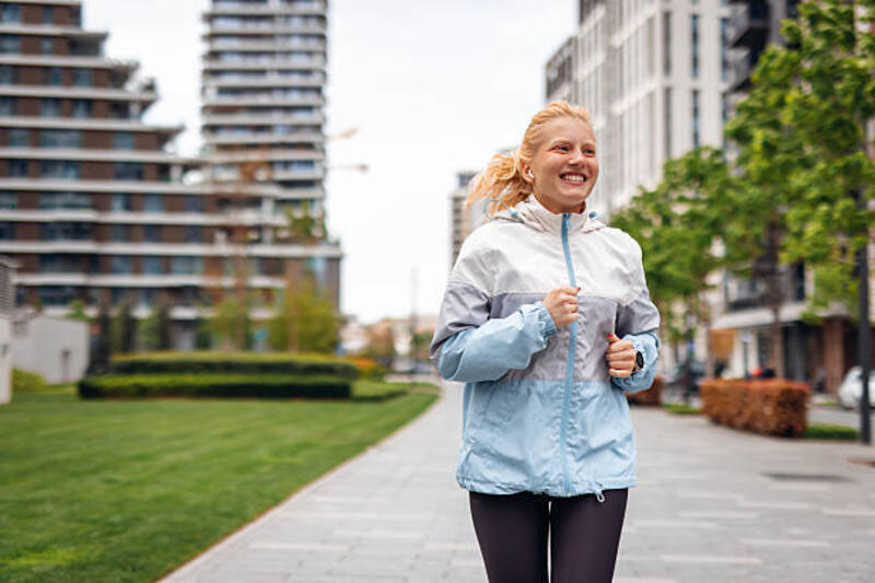wanita muda sporty berlari di kota selama hari berawan - jaket lari potret stok, foto, &amp; gambar bebas royalti