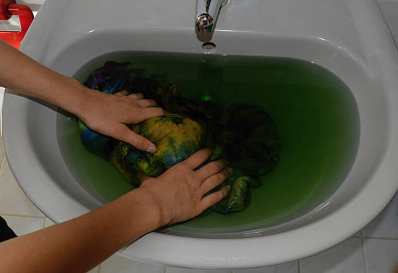 Doing laundry in sink Laundry in sink is losing color. batik wash stock pictures, royalty-free photos &amp; images