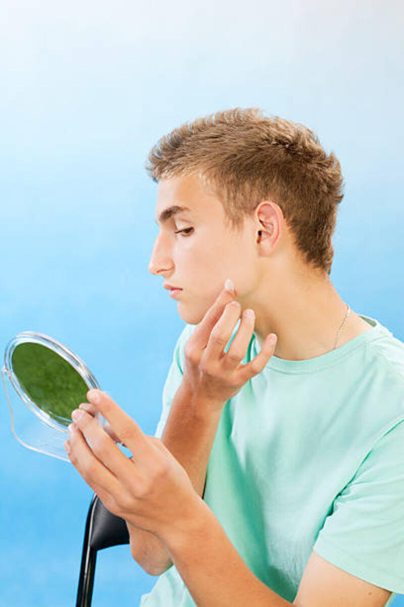 Teenage boy applying cleaning patch to a pimple. Handsome teenage boy applying cleaning patch to a pimple. pimple patch stock pictures, royalty-free photos &amp; images