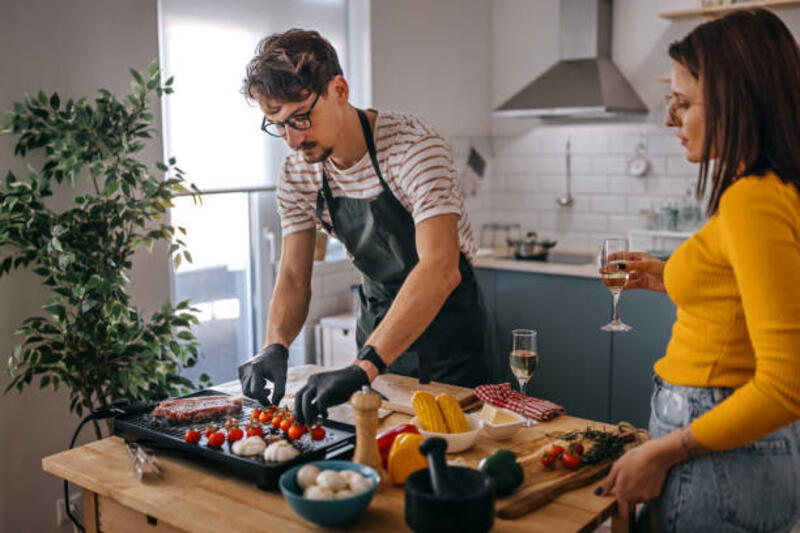 wanita melihat pacar memasak makanan di dapur - electric grill potret stok, foto, &amp; gambar bebas royalti