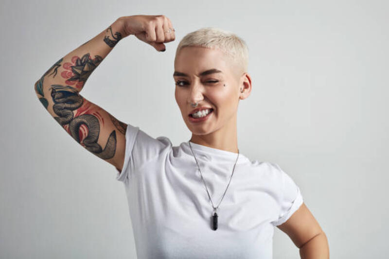 Bringing out the big guns Shot of an attractive young woman flexing her biceps against a grey background short hair women stock pictures, royalty-free photos &amp; images