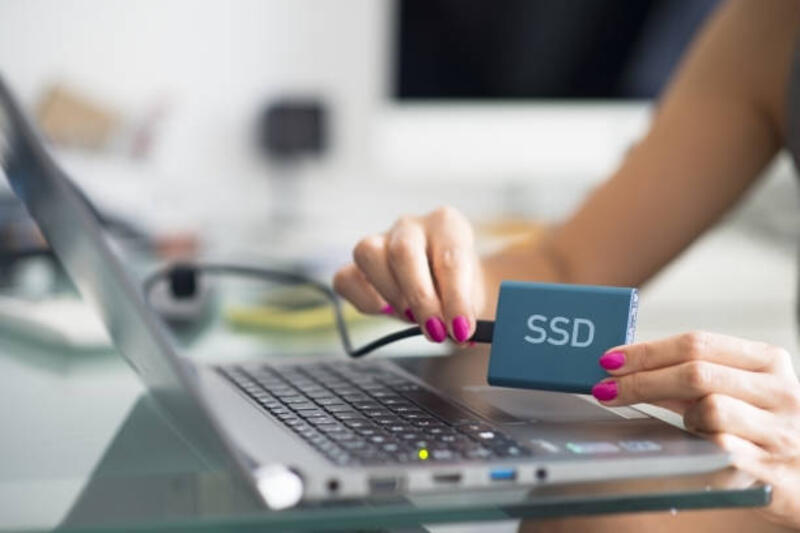 wanita yang menggunakan solid state drive (ssd) di laptop pribadi, peralatan modern yang memberikan kinerja dan keandalan yang lebih baik daripada hdd - using ssd potret stok, foto, & gambar bebas royalti
