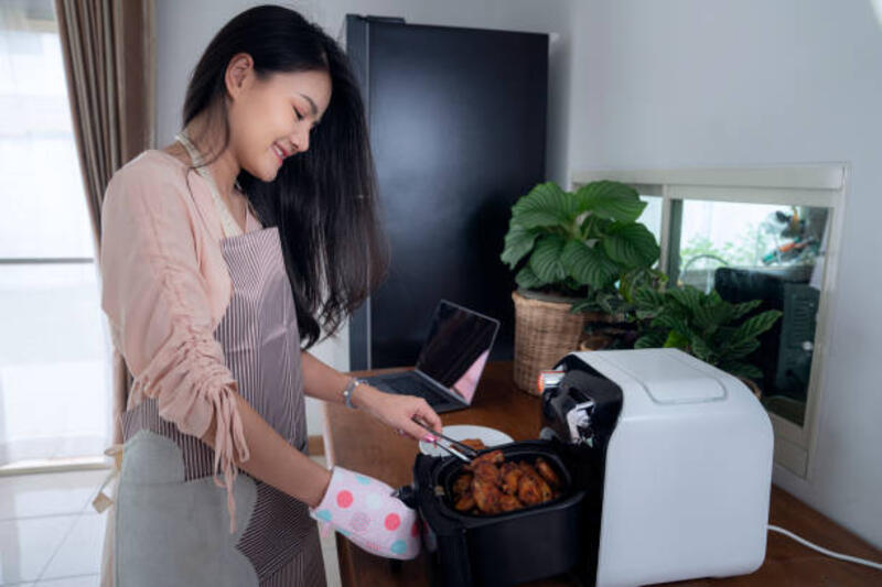 gadis asia menggunakan mesin penggorengan udara untuk memasak ayam - penggoreng udara potret stok, foto, &amp; gambar bebas royalti