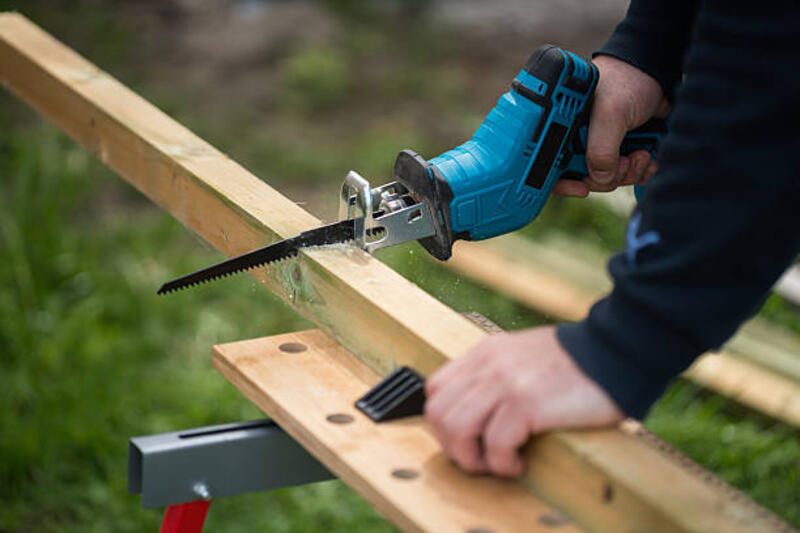 Person Using Electric Reciprocating Saw to Cut Wooden Plank Outdoors Close-up of a person cutting a wooden plank using an electric reciprocating saw outdoors, showcasing woodworking, power tools, and craftsmanship. reciprocating saw stock pictures, royalty-free photos &amp; images