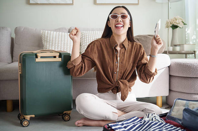 excited young woman sitting with suitcase and passport, celebrating her travel plans at home. - prepare before traveling potret stok, foto, &amp; gambar bebas royalti