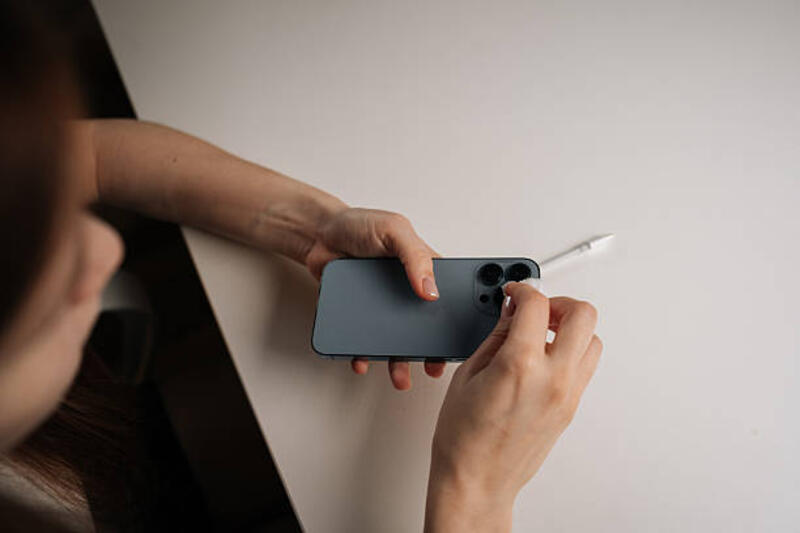 tampilan atas wanita membersihkan lensa kamera smartphone dengan kapas, menjaga kejernihan gambar yang tajam duduk di meja putih, menampilkan perawatan perangkat yang cermat. - membersihkan lensa kamera hp potret stok, foto, &amp; gambar bebas royalti