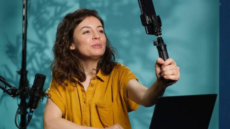 woman using smartphone on selfie stick to capture footage, chatting with fans - shooting content using smartphone potret stok, foto, &amp; gambar bebas royalti