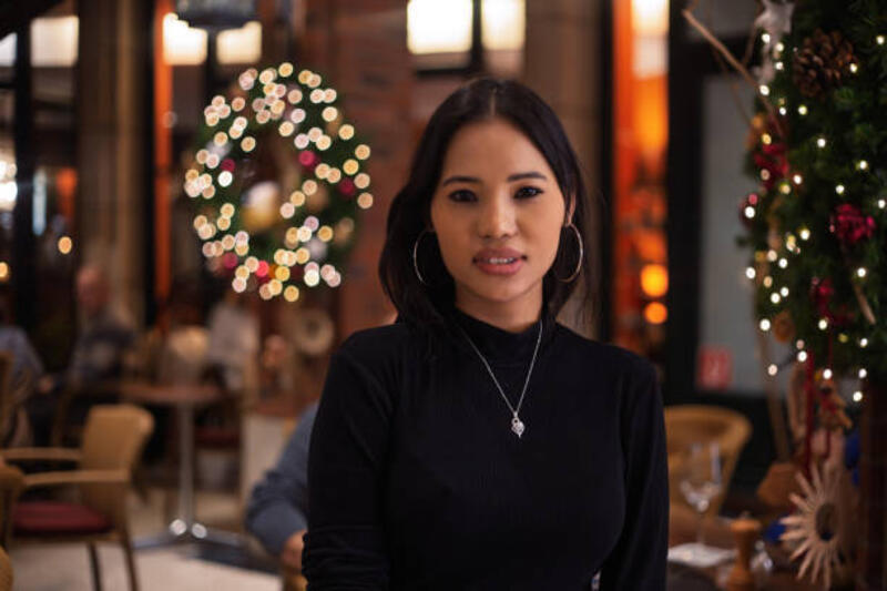 wanita muda asia berpose di restoran yang didekorasi natal - kalung natal potret stok, foto, &amp; gambar bebas royalti