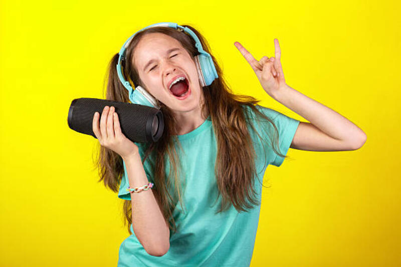gadis pirang muda eropa yang lucu dengan headphone memegang speaker atau kolom musik, mendengarkan musik dan menari dengan latar belakang kuning - speaker mini portable potret stok, foto, & gambar bebas royalti