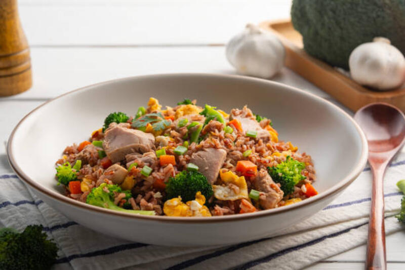 nasi goreng tuna, makanan asia sehat. nasi melati merah merah organik goreng thailand (nasi yang tidak dipoles) dengan ikan tuna kalengan dan telur wortel brokoli dalam piring putih. - nasi goreng tuna potret stok, foto, &amp; gambar bebas royalti